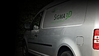 Lieferung sigma3D - Seite und Heck eines silbernes Firmenfahrzeug mit sigma3D Logo.